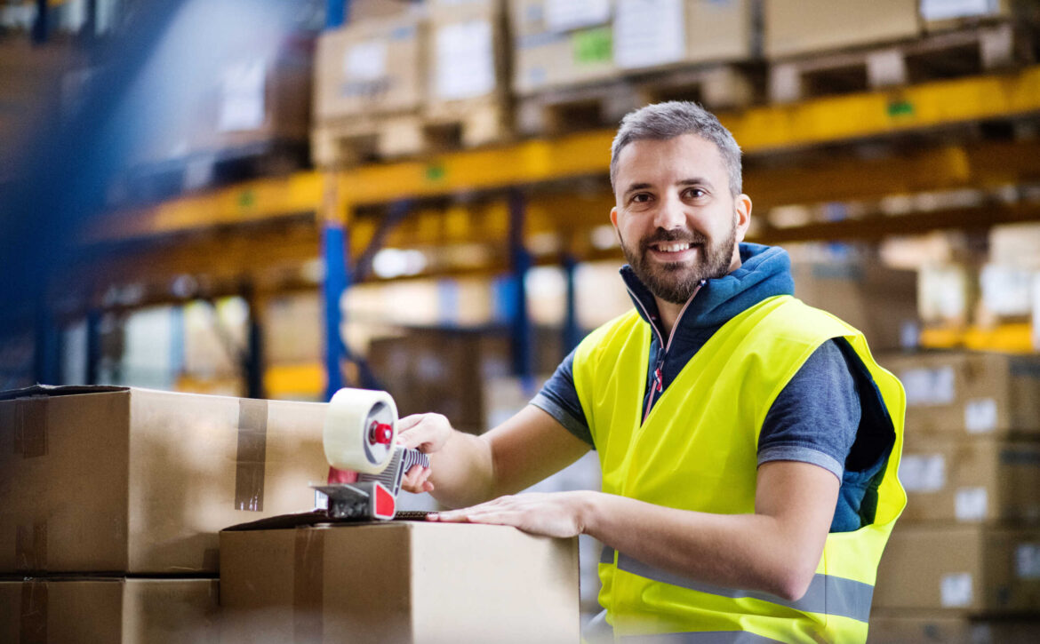 Male warehouse worker sealing cardboard boxes.